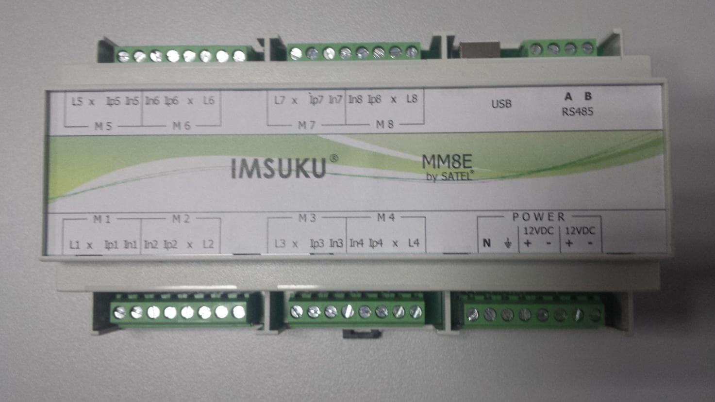 A DIN-rail measuring device labelled IMSUKU MM8E by SATEL, with eight measurement channel groups, USB and RS485 ports, and dual 12-volt supply terminals.